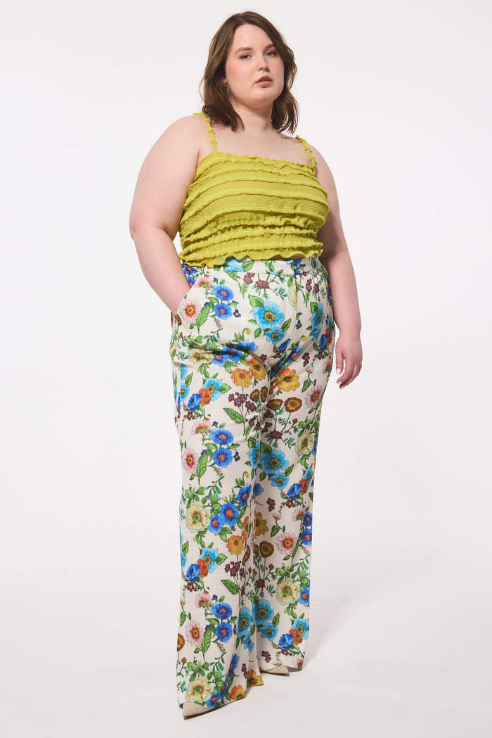 Plus size woman wearing a green top and floral pants on a white background
