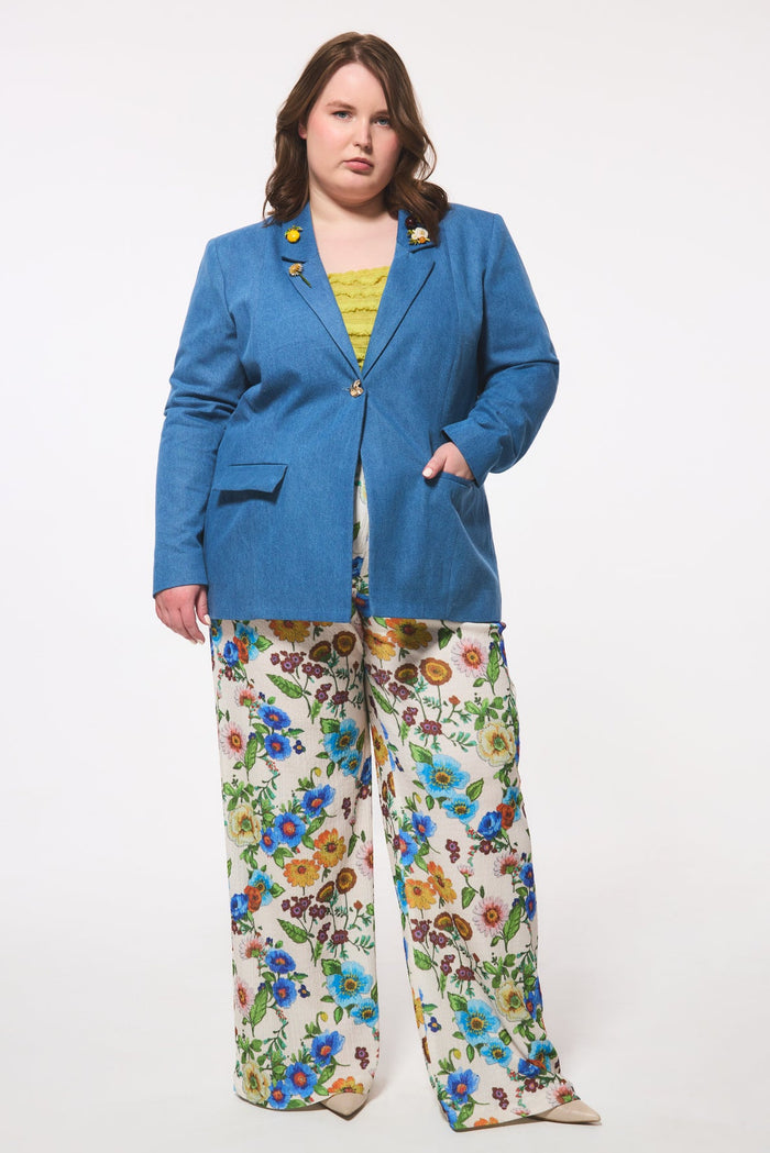 Plus size person wearing a denim blazer and floral pants on a white background