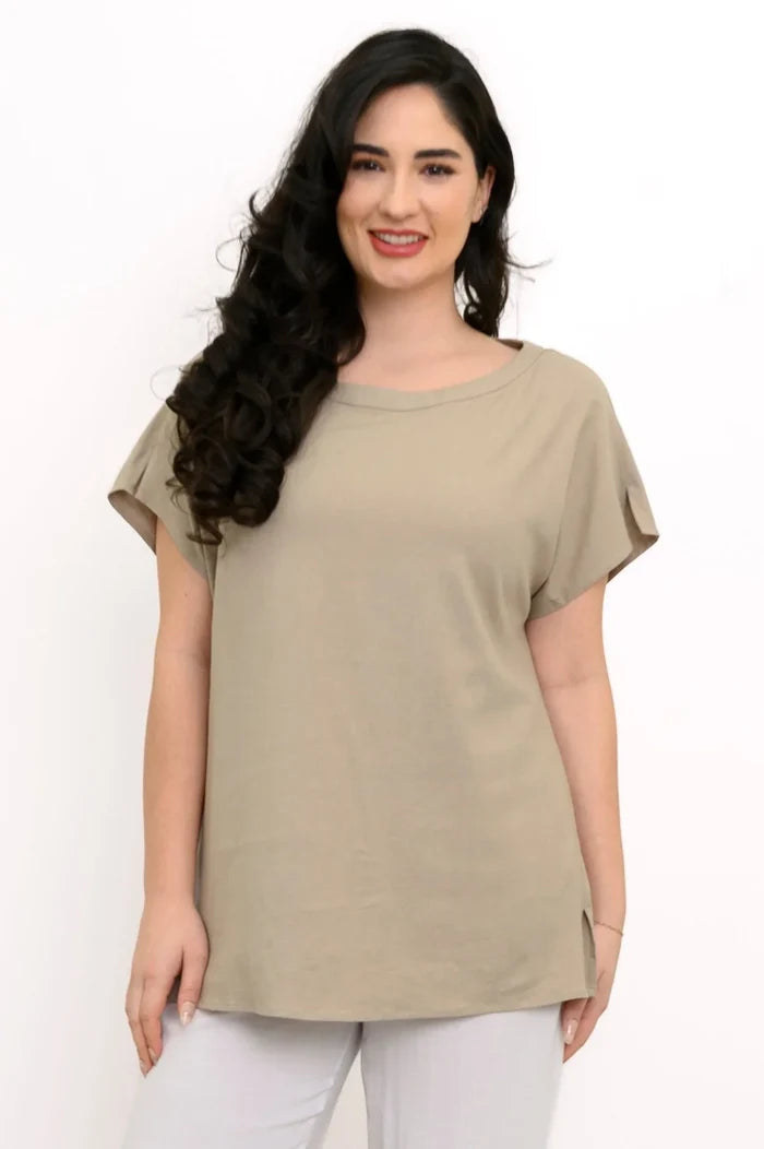 Woman wearing a beige t-shirt and white pants against a white background