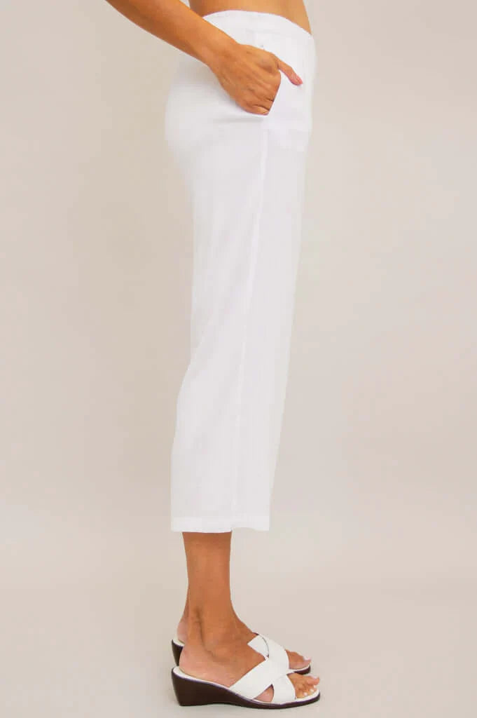 Person wearing white pants and white sandals on a plain background