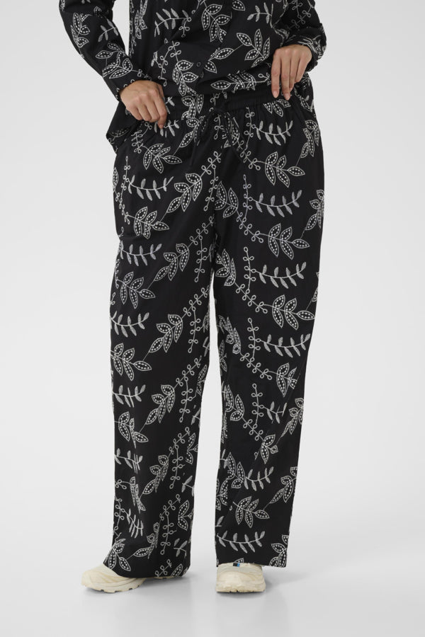 Person wearing black patterned pants on a white background