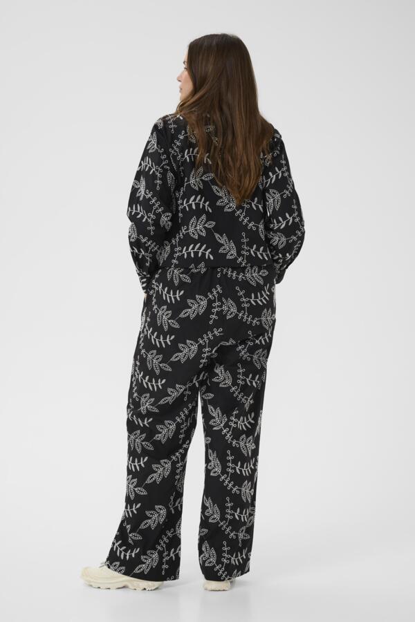 Person wearing a black floral patterned onesie on a white background