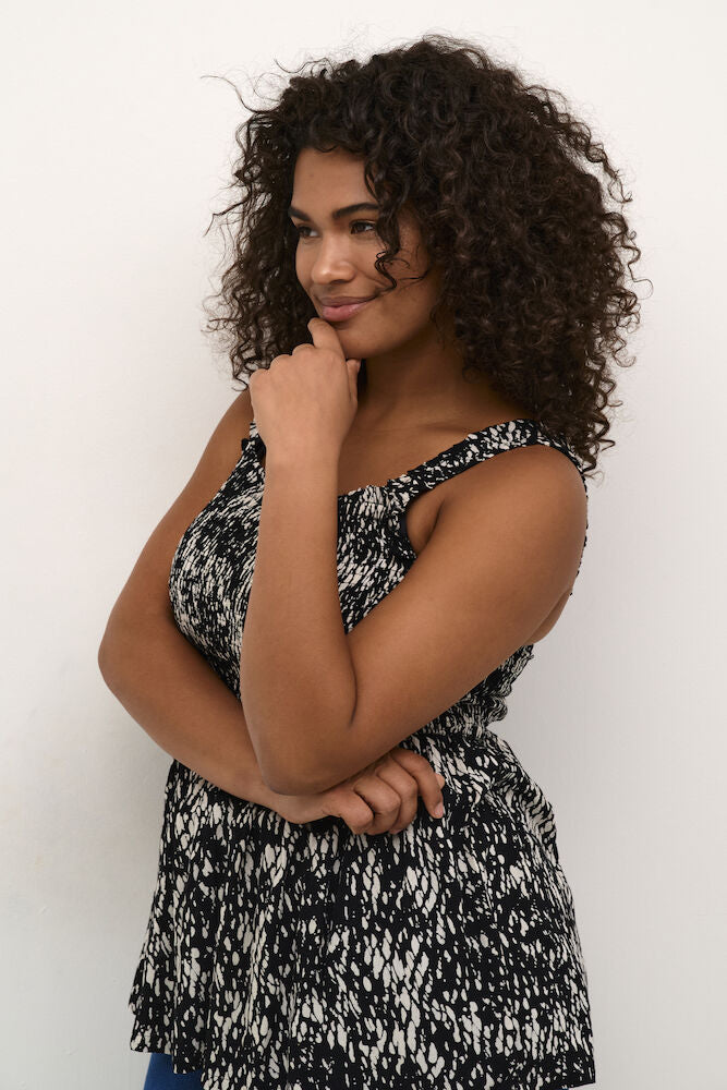 Woman wearing a black and white patterned top against a plain background