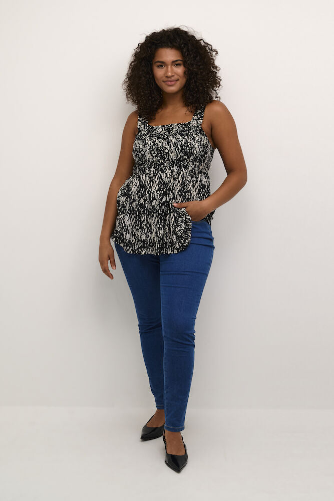 Woman wearing a patterned top and blue jeans on a white background
