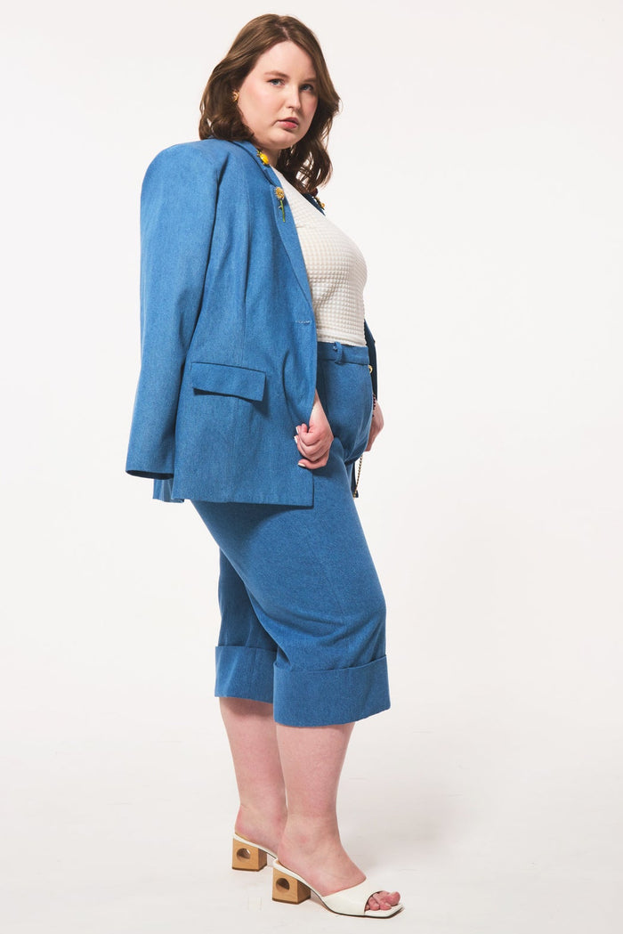 Plus size woman wearing a blue suit with a white top on a white background