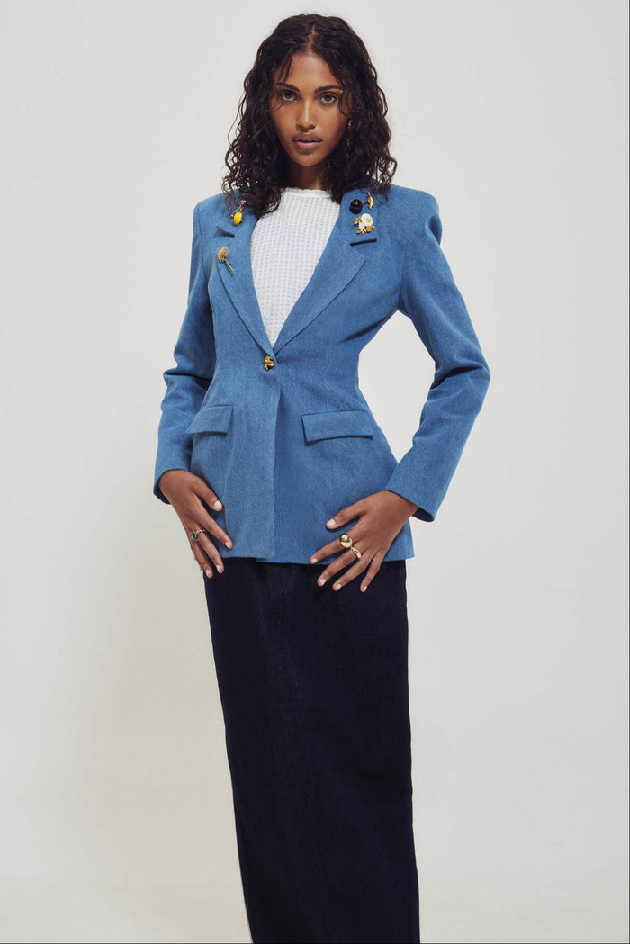 Woman wearing a blue blazer with gold buttons on a white background