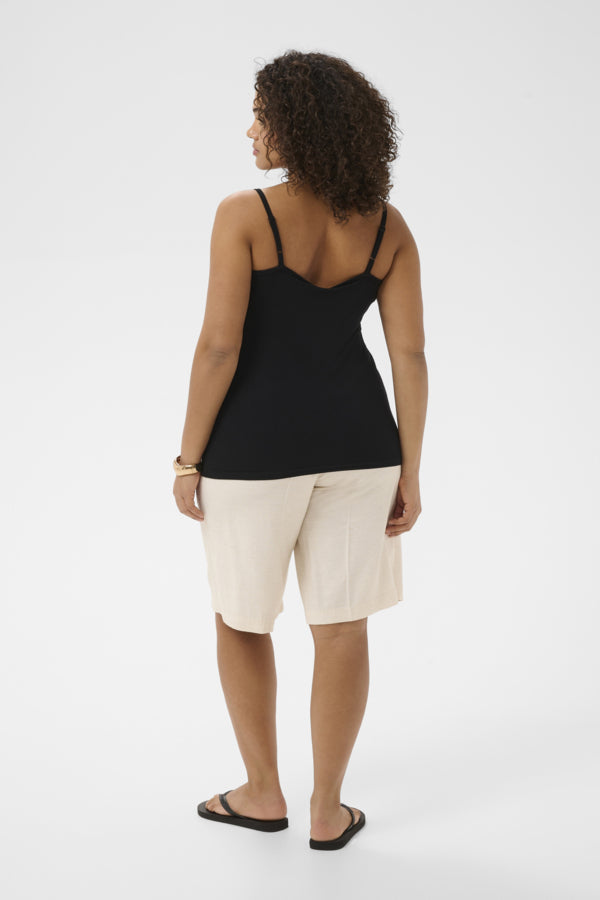 Person wearing a black tank top and white shorts on a white background