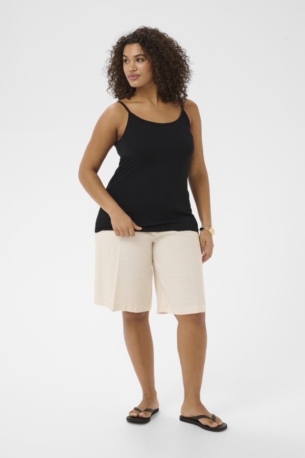 Woman wearing a black tank top and white shorts on a white background