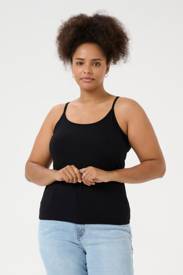 Woman wearing a black tank top and light blue jeans against a white background
