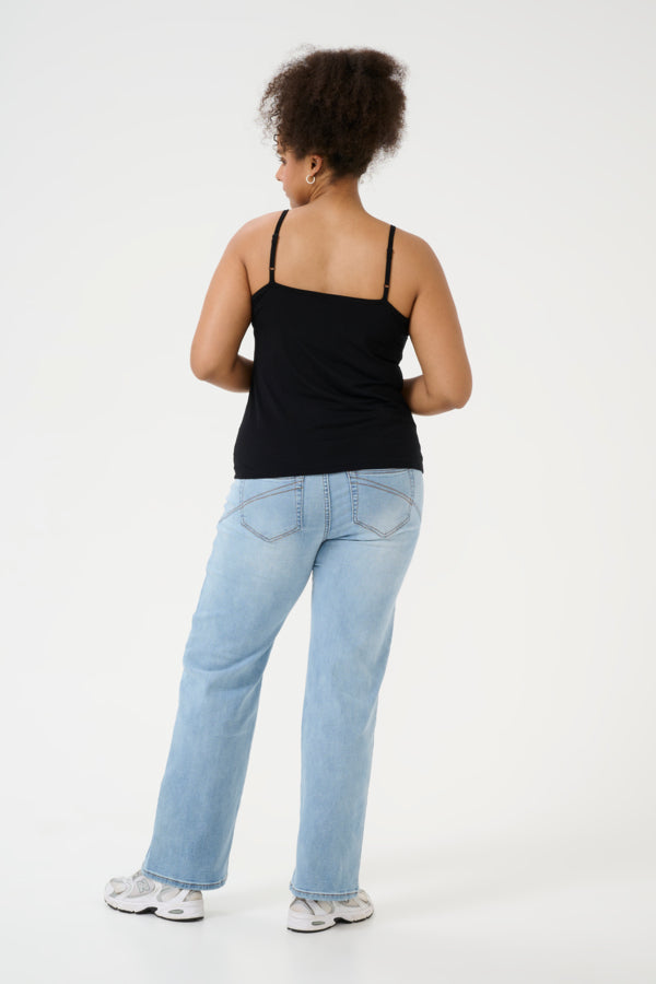 Person wearing a black tank top and light blue jeans on a white background