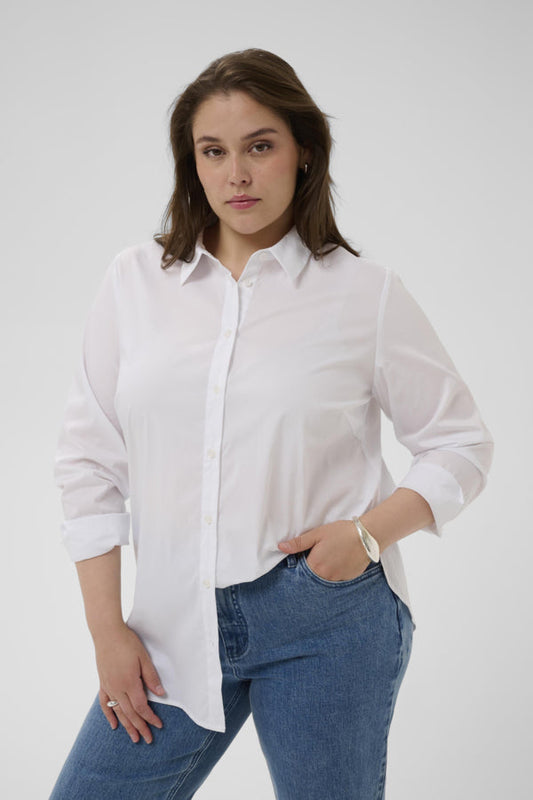 Woman wearing a white shirt and blue jeans against a plain background