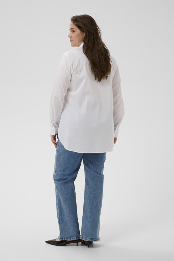 Woman wearing a white shirt and blue jeans on a plain background