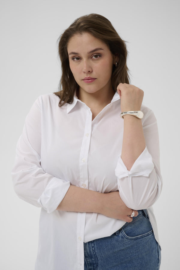 Woman wearing a white shirt and blue jeans against a plain background