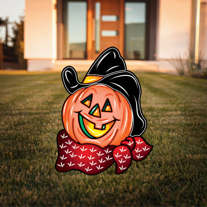 A decorative pumpkin with a cowboy hat and a bow tie placed on a lawn.