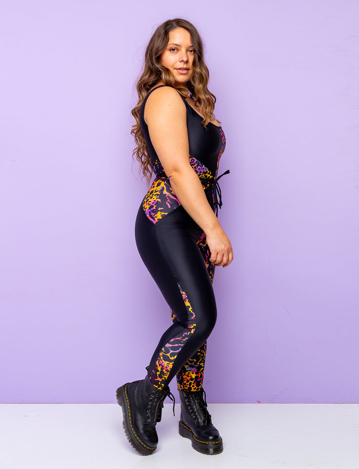 Side view of a woman modelling a purple leopard print catsuit with contrasting black panels.