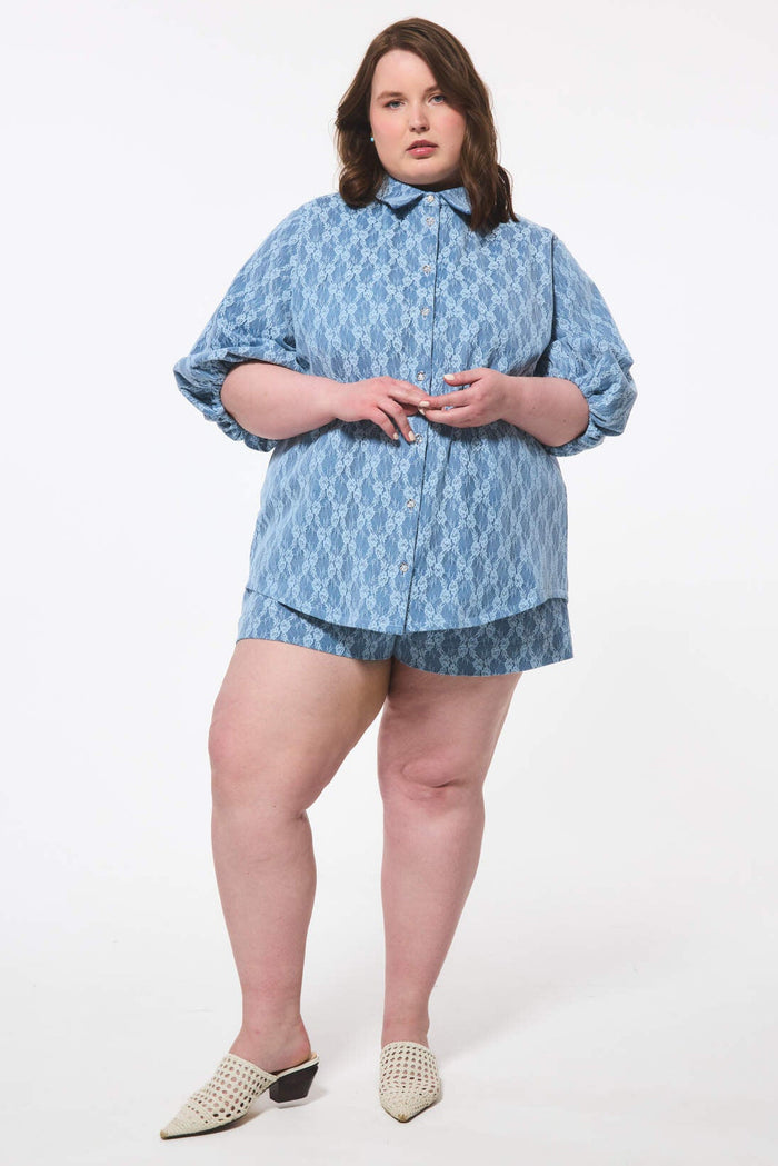 Woman wearing a blue lace & denim outfit on a white background