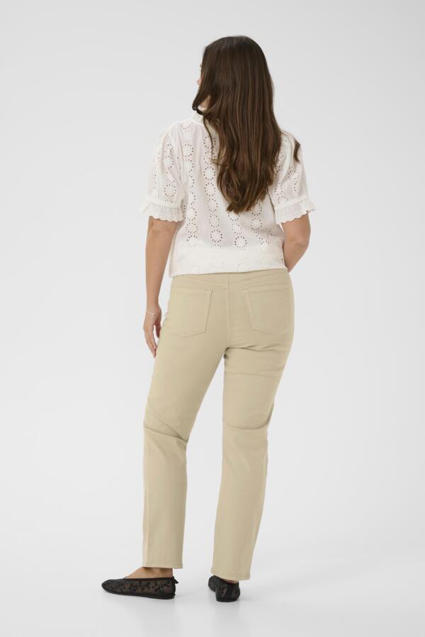 Woman wearing a white lace top and beige pants on a white background