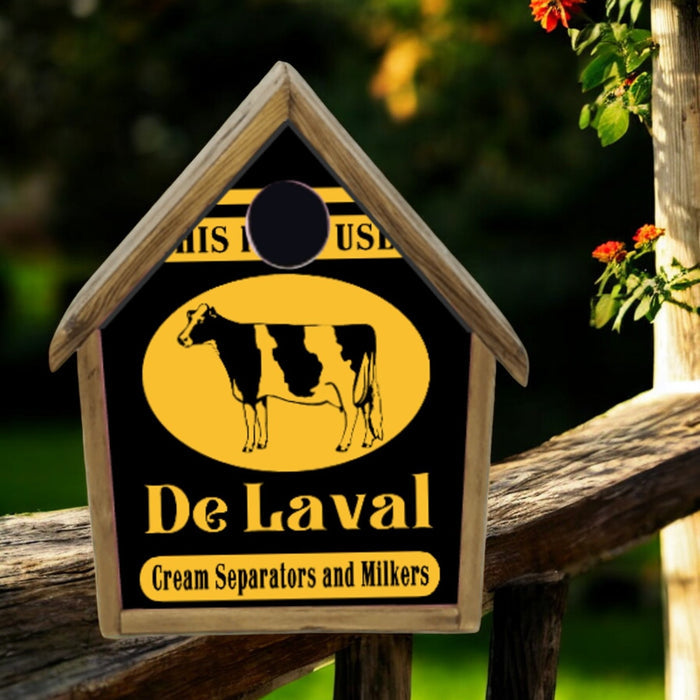 Wooden birdhouse with De Laval logo featuring a cow on a wooden post with flowers in the background