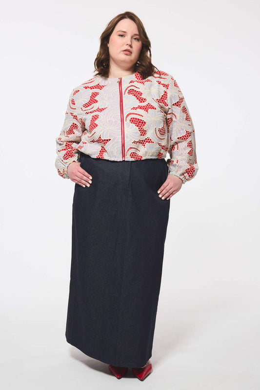 Plus size person wearing a patterned blouse and long dark skirt on a white background