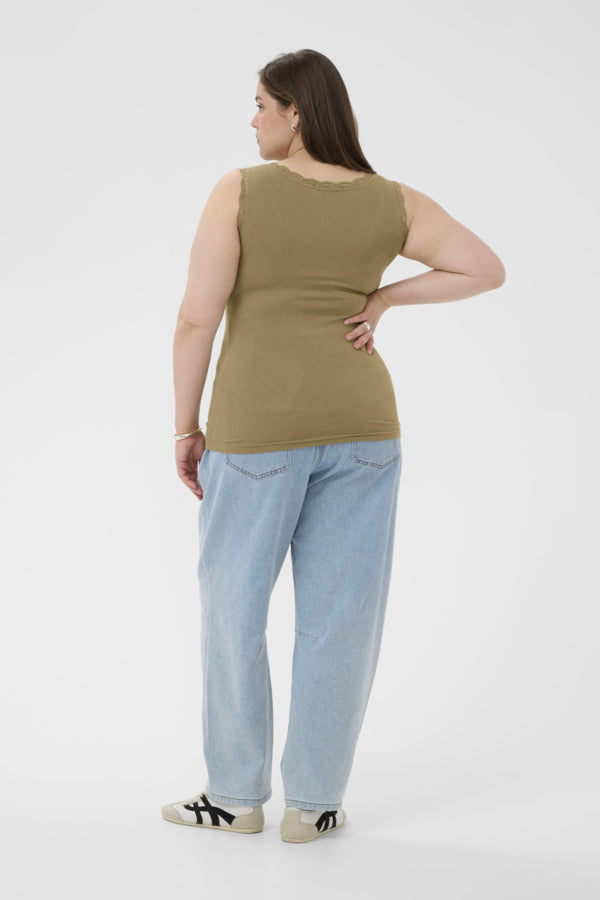 Woman wearing a green sleeveless top and light blue jeans on a white background