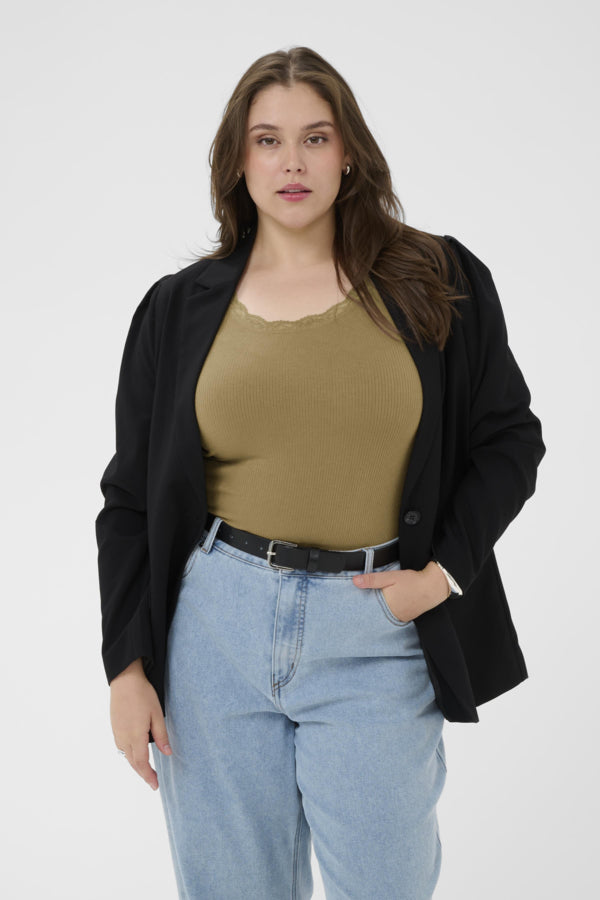 Woman wearing a black cardigan, beige top, and blue jeans on a white background