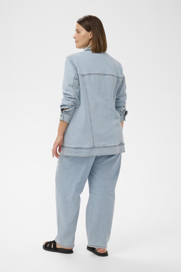 Woman wearing a light blue denim outfit on a white background