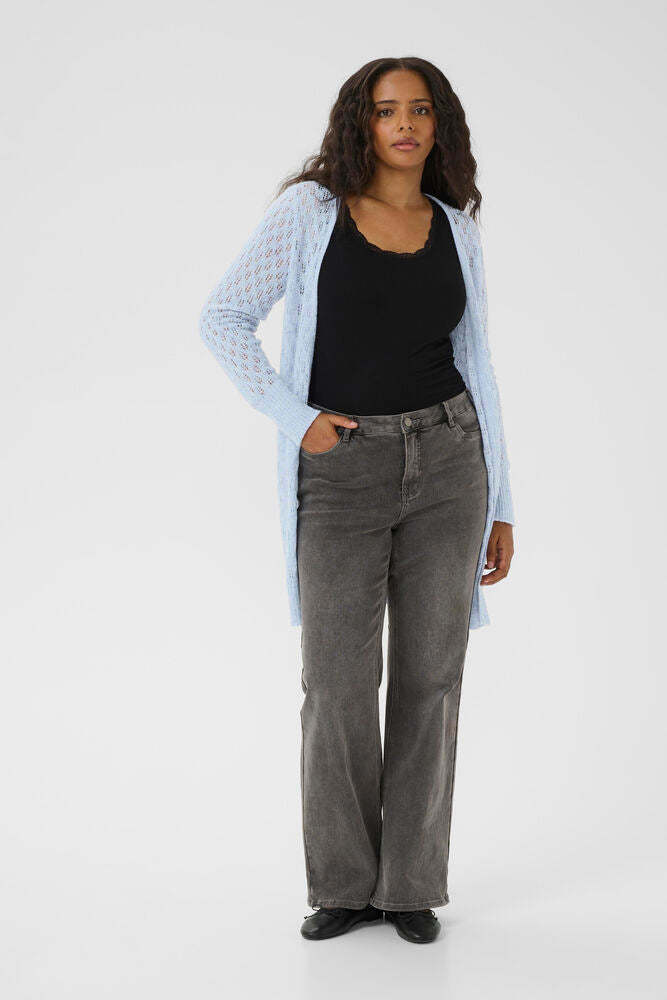 Woman wearing a black top, light blue cardigan, and gray pants on a white background