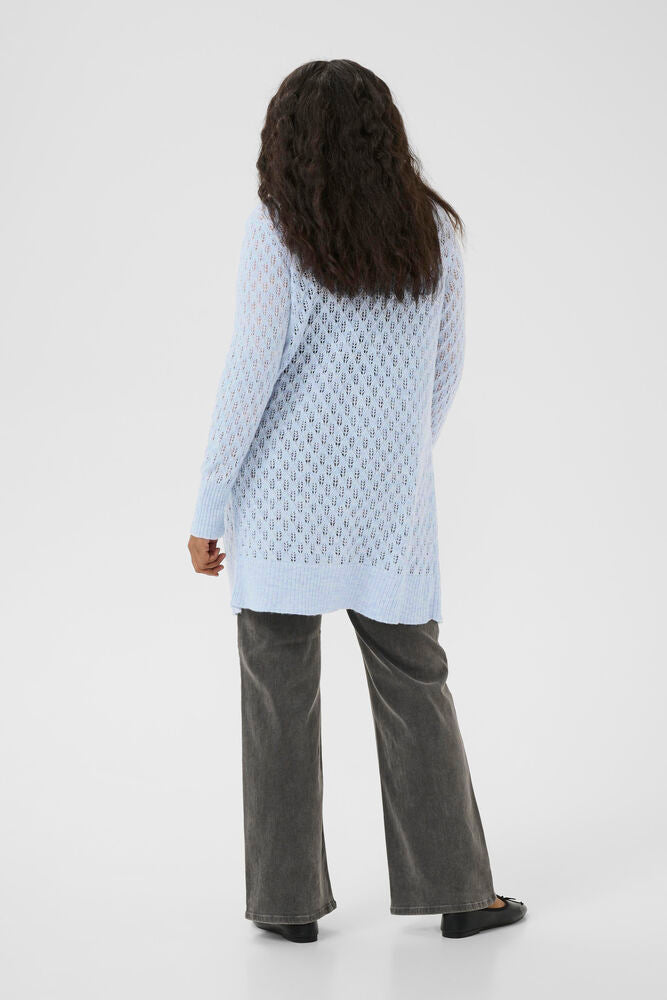 Person wearing a light blue textured sweater and gray pants on a white background