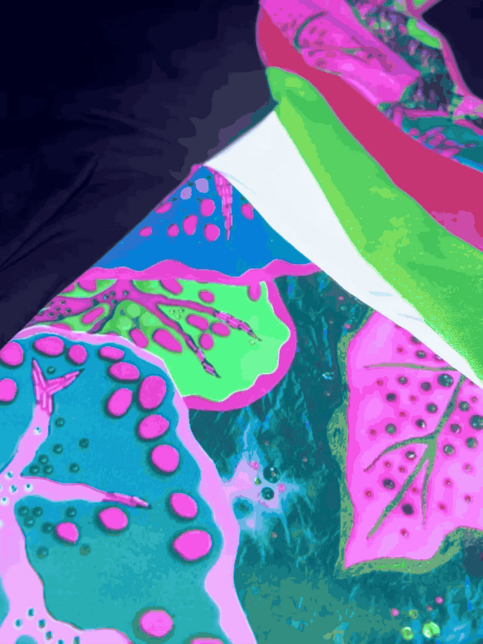 Flashing lights showing the reflective panels and uv patterns on a green and pink patterned catsuit
