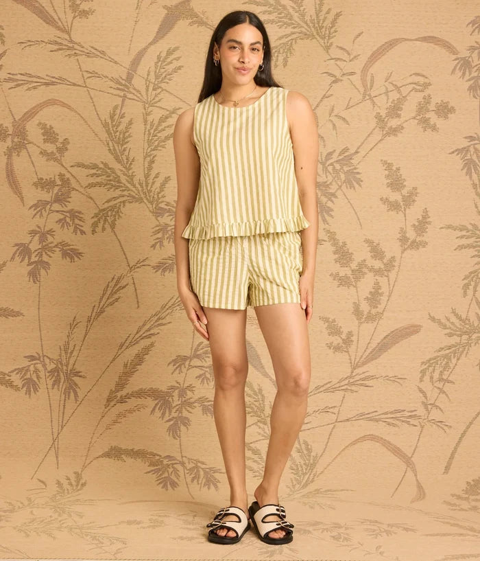 Woman wearing a yellow striped outfit against a beige background with leaf patterns