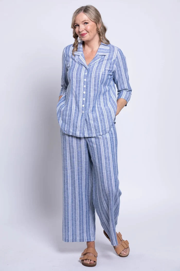 Woman wearing a blue and white striped pajama set on a plain background