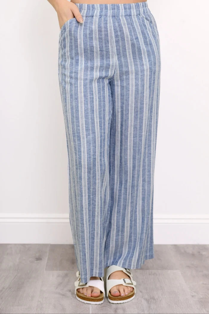 Blue and white striped pants worn by a person on a plain background