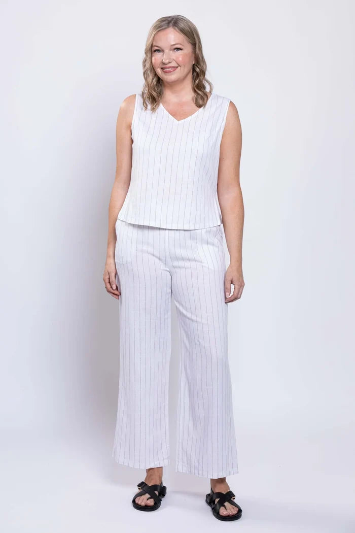 Woman wearing a white sleeveless top and wide-leg pants on a white background