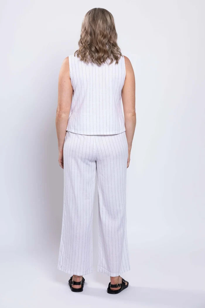 Woman wearing a white sleeveless top and wide-leg pants with vertical stripes on a white background