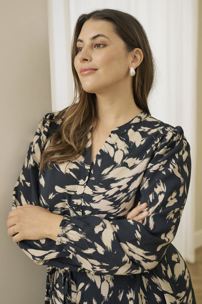 Woman wearing a dark blue and beige patterned dress indoors.