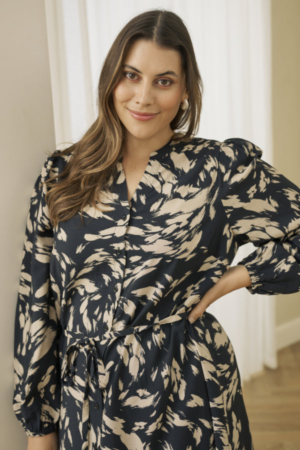 Woman wearing a black and beige patterned dress indoors.