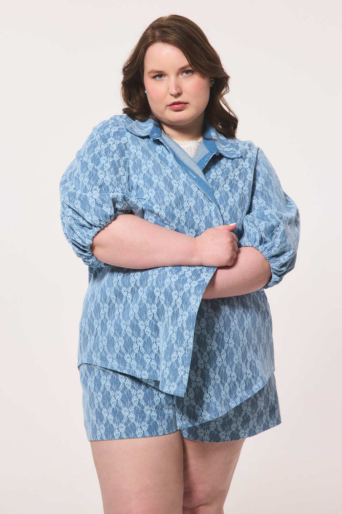 Plus size person wearing a blue lace outfit on a white background