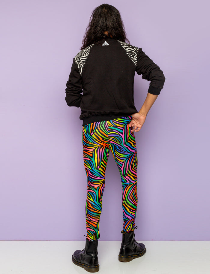 Back view of man modelling rainbow zebra mens leggings and black zebra print sweatshirt.