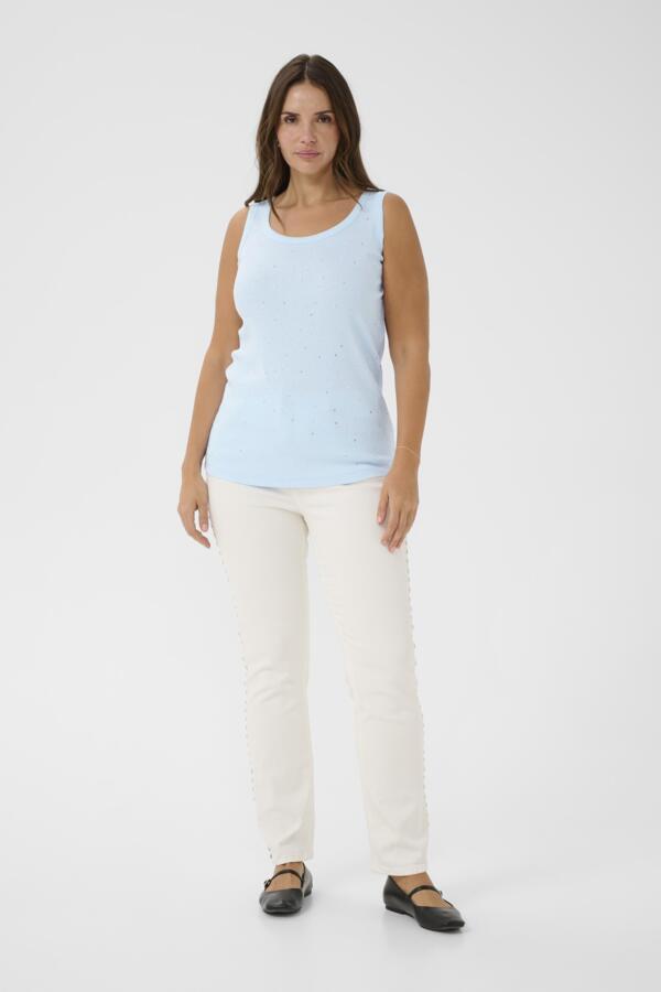 Woman wearing a light blue sleeveless top and white pants on a white background