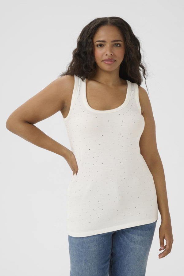Woman wearing a white tank top with small patterns and blue jeans on a white background