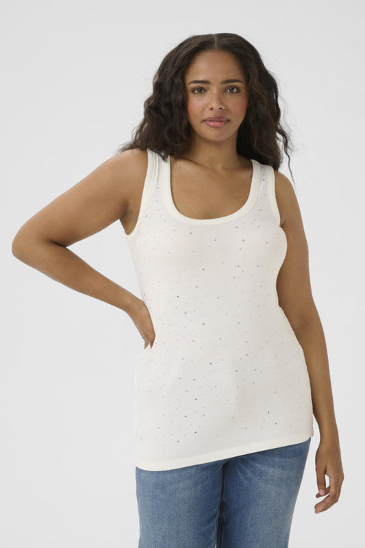 Woman wearing a white tank top with small patterns and blue jeans on a white background