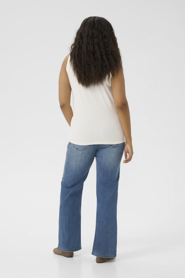 Person wearing a white sleeveless top and blue jeans on a white background