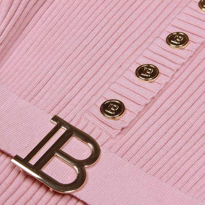 Close-up of a ribbed knit midi dress in pink with gold button details and a decorative buckle