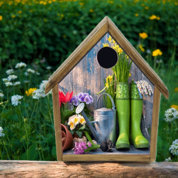 Wooden birdhouse with garden-themed decorations including green boots, flowers, and a watering can, set against a garden background.