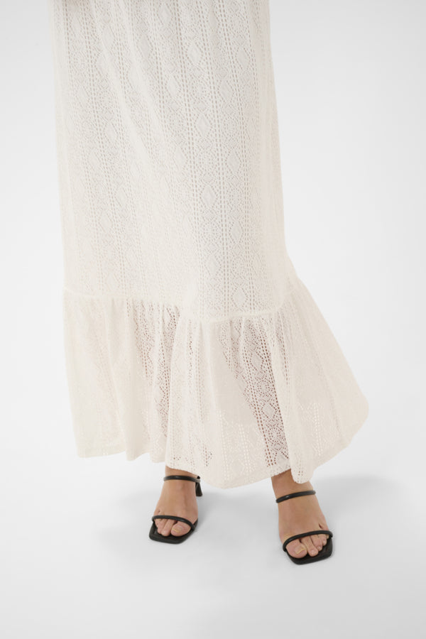 Long beige dress with black sandals on a white background
