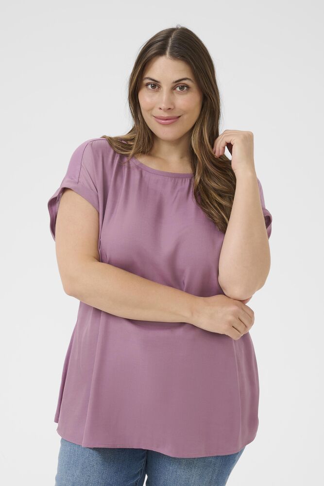 Woman wearing a purple tunic and blue jeans on a white background
