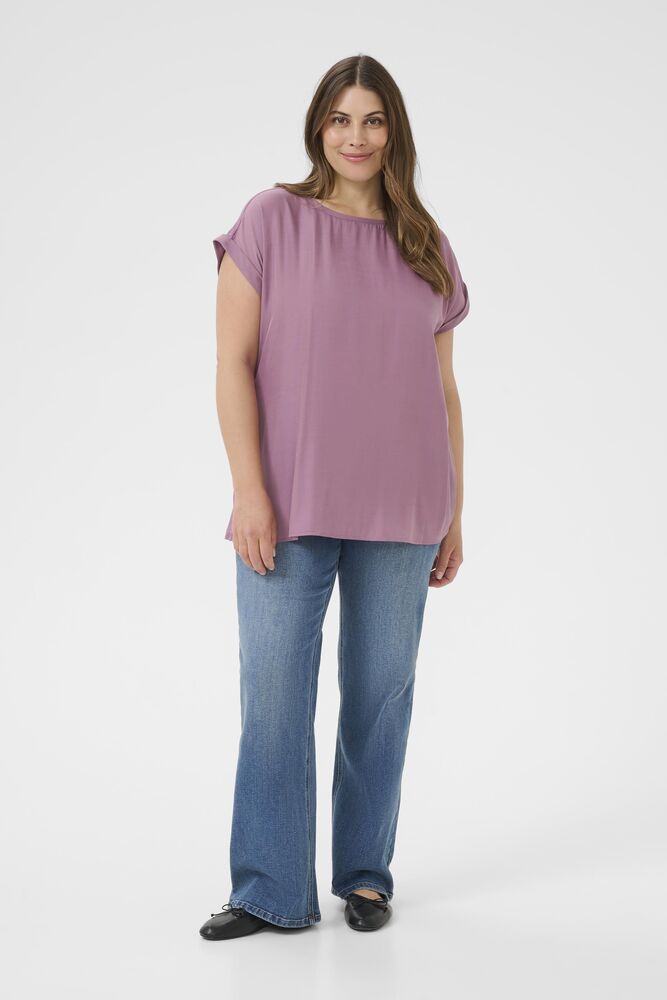Woman wearing a mauve top and blue jeans on a white background